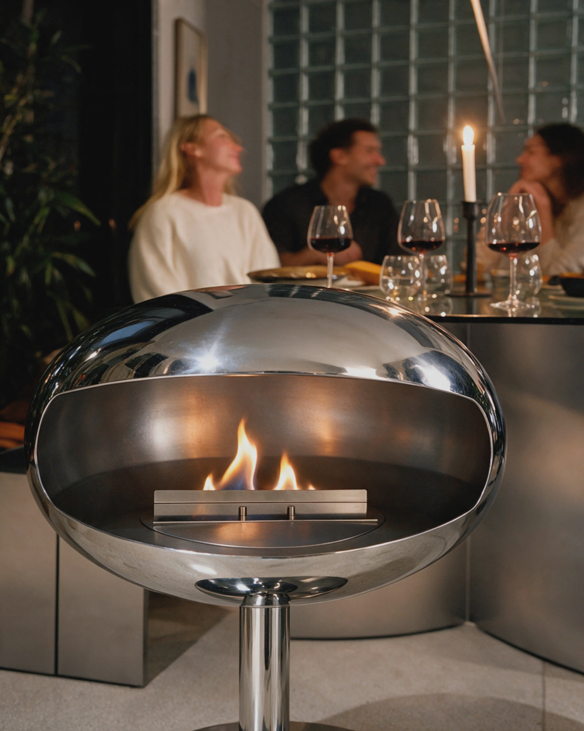 Cheminée bioéthanol Kumo chrome allumée près d'une table lors d'un dîner
