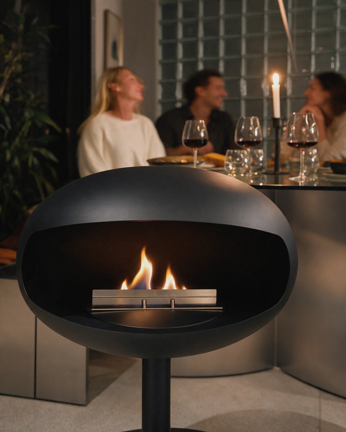 Cheminée bioéthanol Kumo noir mat allumée près d'une table lors d'un dîner